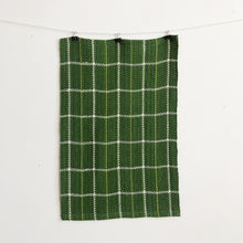 Load image into Gallery viewer, a handwoven green checked teatowel hangs on a clothesline in front of a white wall
