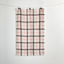 Load image into Gallery viewer, a handwoven white, pink and brown teatowel hangs on a clothesline in front of a white wall

